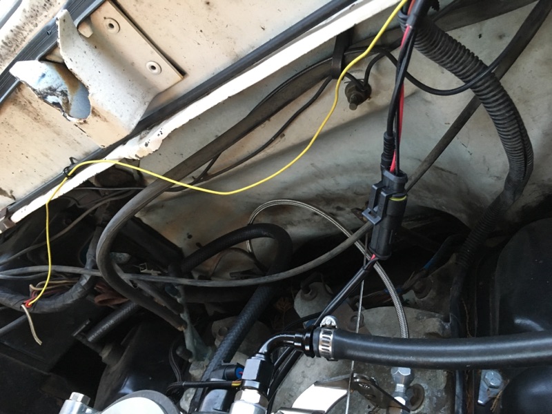 1979 Ford Bronco engine bay with wires, hoses, and electrical connector.