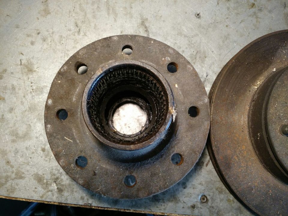 Rusty wheel hub with splines and brake rotor on a metal surface