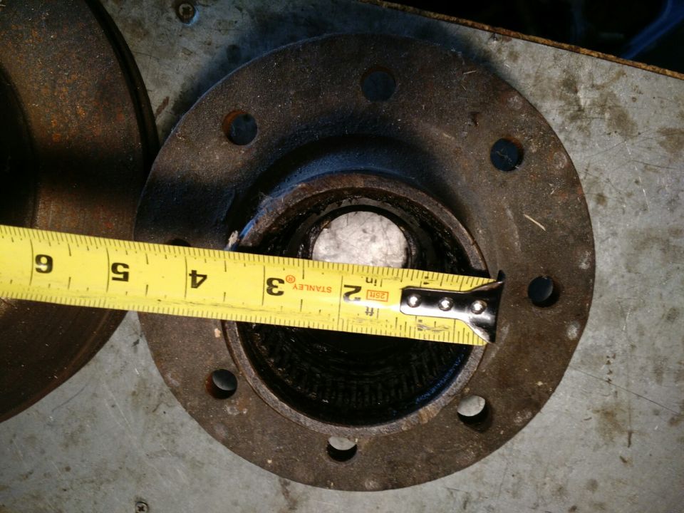 Measuring tape across a rusty hub assembly opening
