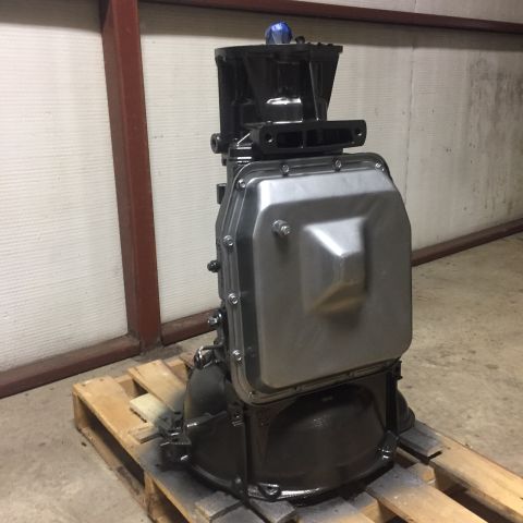 1982 Ford Bronco - A black and silver transmission assembly is mounted on a wooden pallet. The transmission has a large, silver oil pan and a black upper hous…