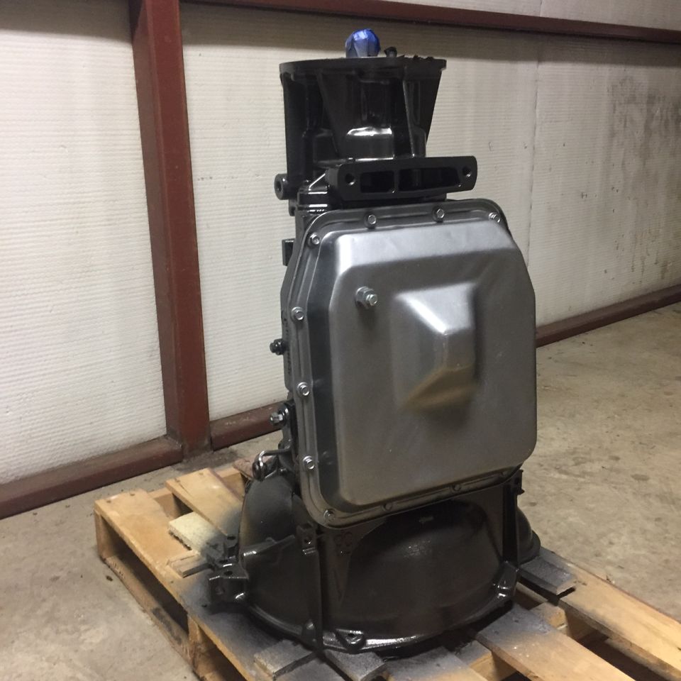 Black and silver transmission assembly on a wooden pallet.