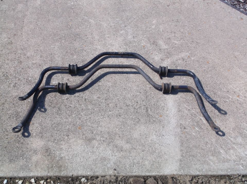 Two black sway bars with rubber bushings on concrete