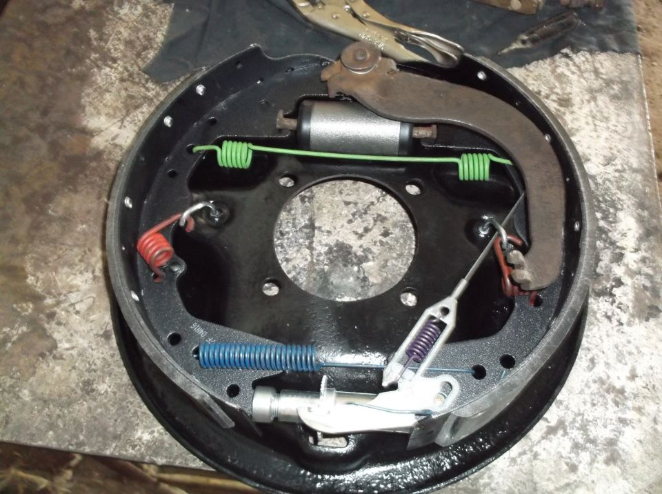 Drum brake assembly with springs, wheel cylinder, and brake shoes.
