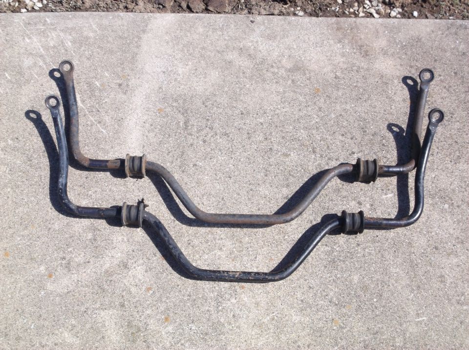 Two automotive sway bars with bushings on concrete