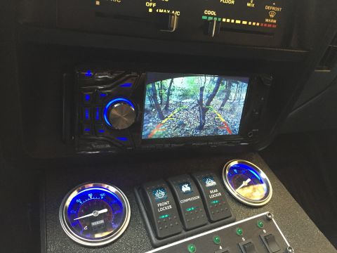 1988 Ford Bronco - The interior of a vehicle shows a car stereo with a backup camera display, three toggle switches labeled "FRONT LOCKER", "COMPRESSOR", and…