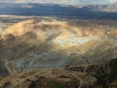 1988 Ford Bronco - An aerial view of a massive open-pit mine with terraced excavations and distant mountains under a cloudy sky.