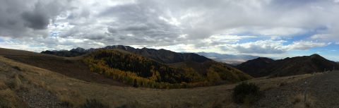1988 Ford Bronco - A panoramic view of a mountain landscape during autumn. The mountains are covered in trees with yellow and green foliage, with some snow vi…