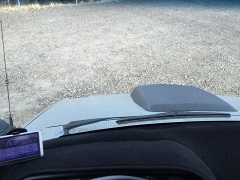 1988 Ford Bronco - View from inside a vehicle looking at the dashboard, hood, and a gravel lot. A GPS device is mounted on the dashboard.