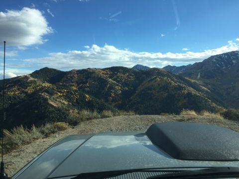 1988 Ford Bronco - A view from inside a vehicle looking out at a mountain landscape during the fall. The hood of the vehicle and part of the windshield are vi…