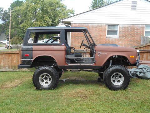 1972 Ford Bronco - The side view of a lifted, custom 1972 Ford Bronco with its doors removed, showcasing its roll cage and off-road tires. The vehicle has a t…