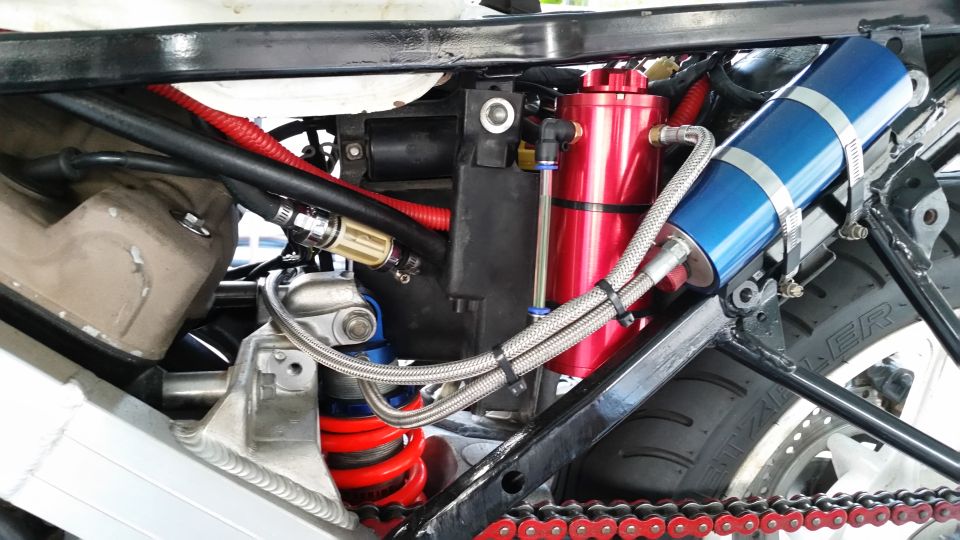 Motorcycle engine bay with red oil catch can and blue coolant reservoir