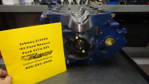 1982 Ford Bronco - A blue Ford 427w EFI engine block is shown with a yellow card in front of it. The card has text including "Johnny J16086", "'82 Ford Bronco…