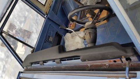 1973 Ford Bronco - Interior view of a classic vehicle's dashboard area, showing a steering wheel, shift lever, and a dark gray dashboard trim piece. The vehic…