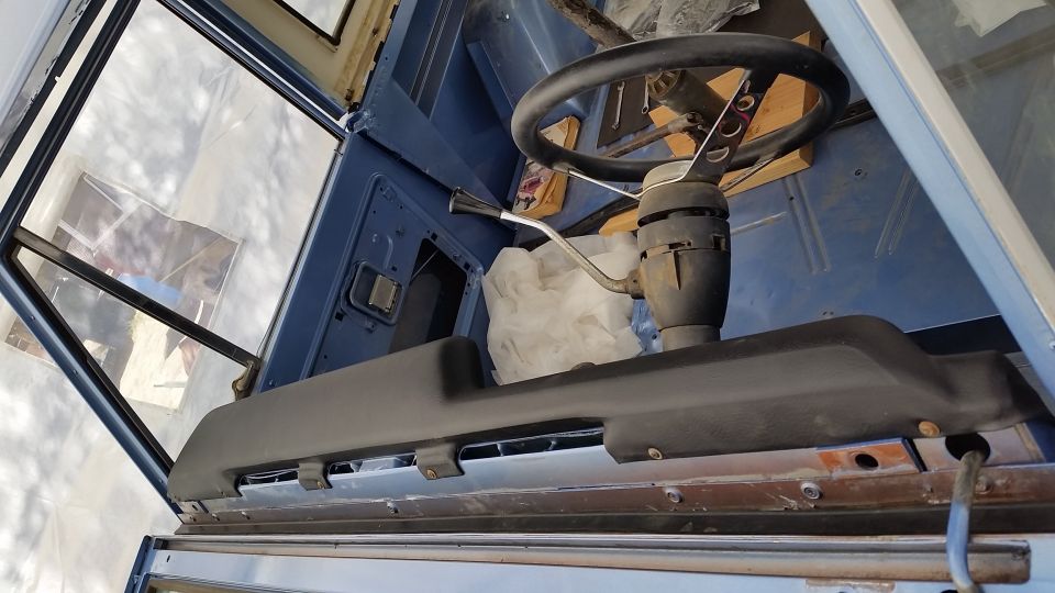 Interior of a classic blue vehicle, showing steering wheel, shifter, and dashboard trim.
