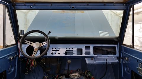 1973 Ford Bronco - Interior view of a vintage blue Ford Bronco under restoration. The dashboard is partially disassembled, revealing the steering wheel, gear…