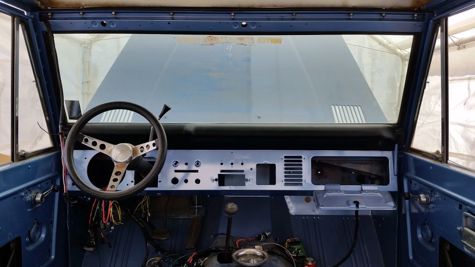 Interior of a blue Ford Bronco showing the dashboard, steering wheel, and gear shifter.