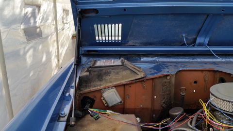 1973 Ford Bronco - The open hood of a blue 1973 Ford Bronco reveals the engine bay and part of the interior firewall. Visible components include the air filte…