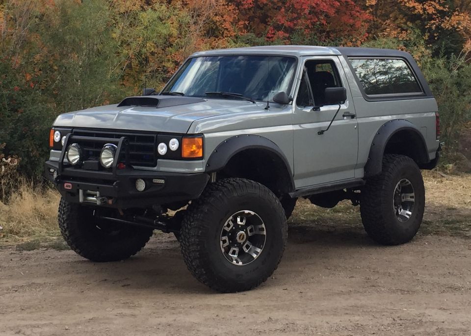 1988 Ford Bronco with lift kit, aftermarket bumper, and hood scoop.