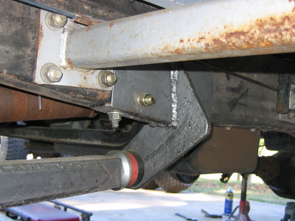 Custom welded bracket attached to vehicle frame with bolts, part of suspension system.
