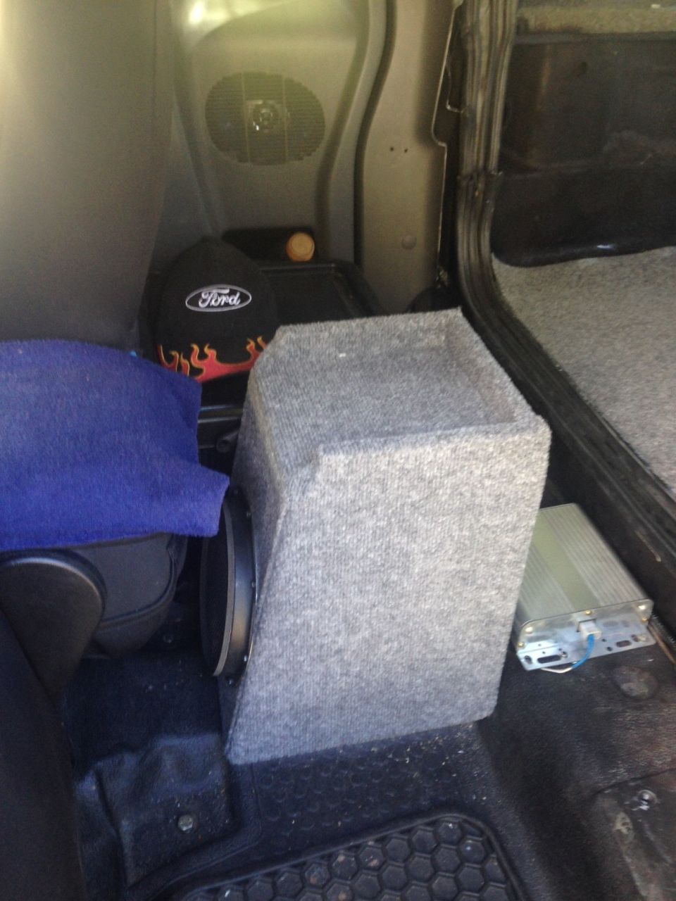 Interior of a Ford Ranger with a subwoofer, Ford hat, and amplifier.
