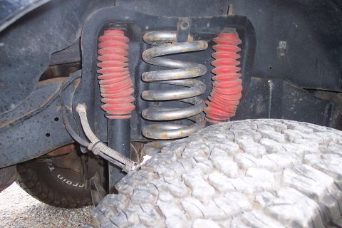 1995 Ford Bronco - Close-up of a vehicle's front suspension system, showing a coil spring and shock absorbers.