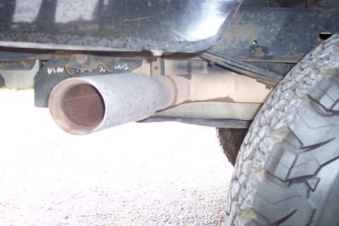 1995 Ford Bronco - Close-up view of a vehicle's exhaust pipe and tire, with visible rust on the frame.