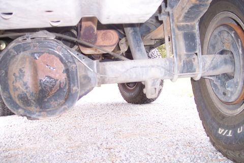 1995 Ford Bronco - Close-up view of the rear axle and suspension system of a vehicle, highlighting the differential and leaf spring assembly.