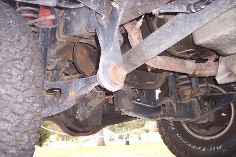 1995 Ford Bronco - The underside of a vehicle reveals its suspension, exhaust system, and tires.