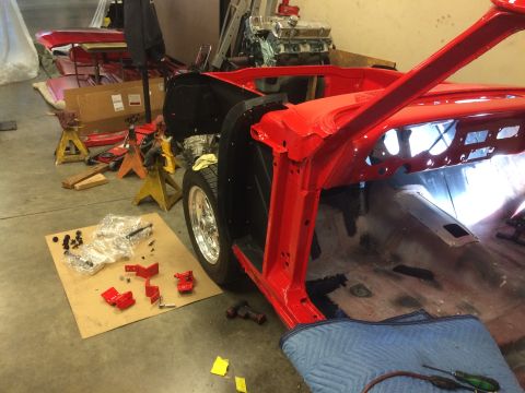 1964 Ford Fairlane - A red 1964 Ford Fairlane is undergoing restoration in a workshop, with parts laid out on the floor.