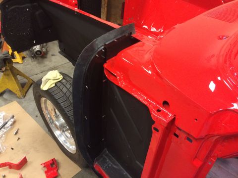 1964 Ford Fairlane - Close-up view of a red car's wheel well and fender area, likely during restoration or assembly.