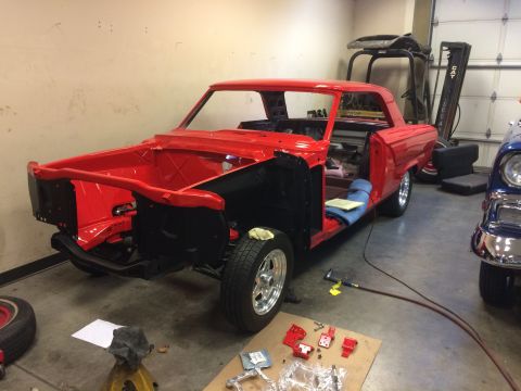 1964 Ford Fairlane - A red 1964 Ford Fairlane coupe is in a garage, stripped down for restoration, with another classic car visible to the right.