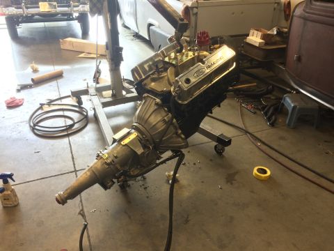 1964 Ford Fairlane - A Ford V8 engine and transmission assembly is mounted on an engine stand in a garage, ready for installation.
