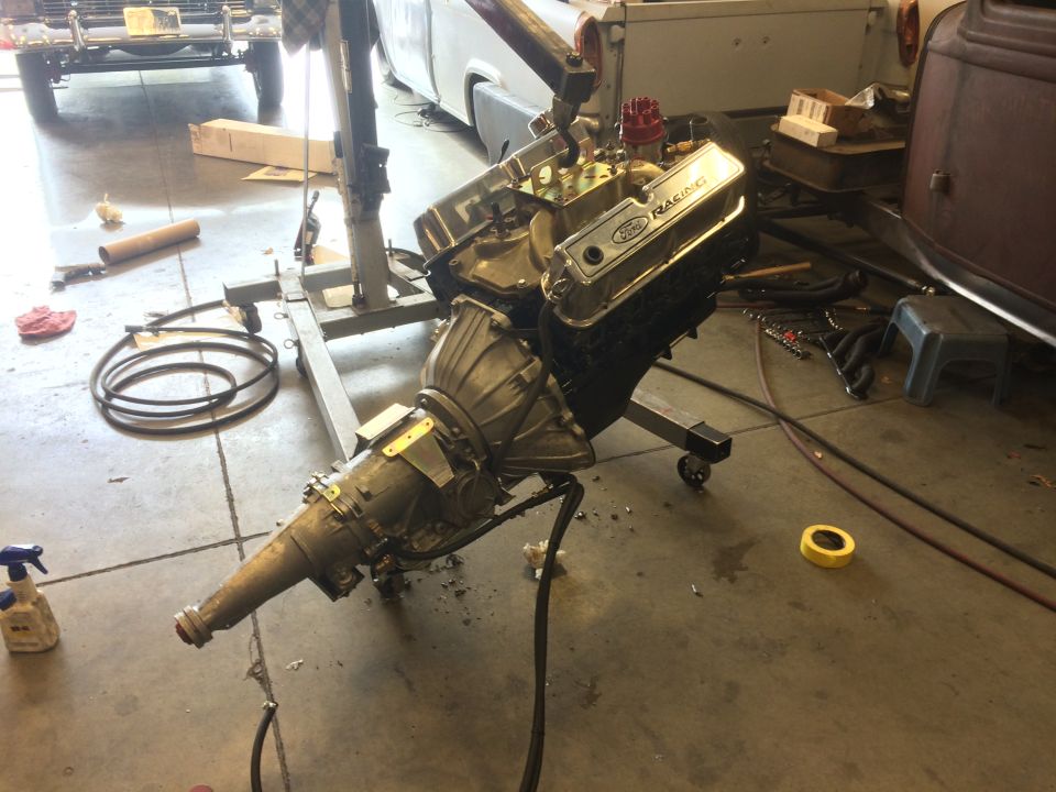 Ford V8 engine with chrome valve covers and transmission assembly on an engine stand