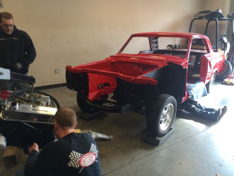 1964 Ford Fairlane - A red 1964 Ford F-100 pickup truck body is being worked on, with an engine and transmission nearby.