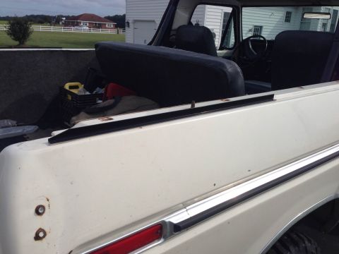 1979 Ford Bronco - The interior of a white 1978 Ford Bronco shows black seats and a cargo area with various items.