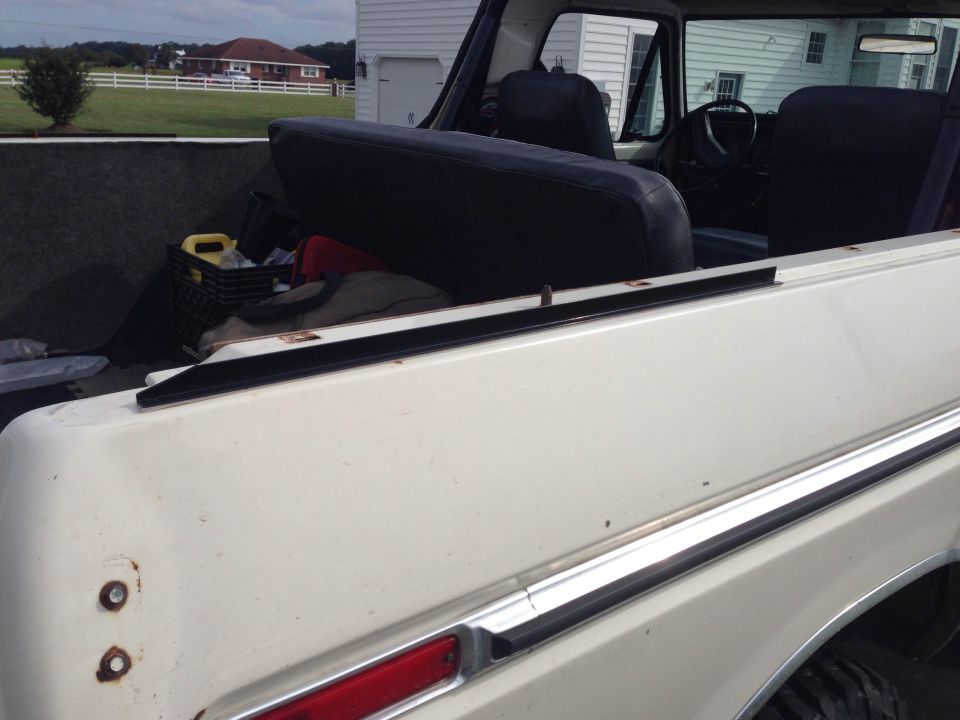 White 1978 Ford Bronco interior with black seats and cargo area containing a yellow jug and black basket