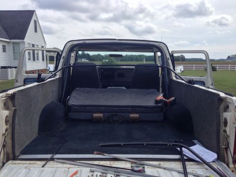 1979 Ford Bronco - Rear view of a 1978 Ford Bronco's interior, showing seats and cargo area with tools.