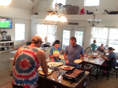 1979 Ford Bronco - A group of people are gathered around a table in a home, preparing and eating food. There is a television visible in the background.
