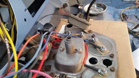 1973 Ford Bronco - Close-up of a disassembled instrument cluster and wiring harness with an ignition coil and colored wires laid on cardboard.