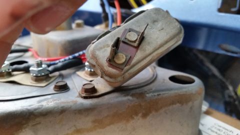1973 Ford Bronco - A close-up view of a vintage electrical component, possibly a voltage regulator, with two terminals and wiring attached. The component is m…