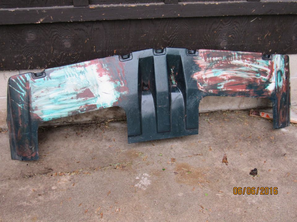Scuffed and weathered dark green vehicle part with paint remnants.