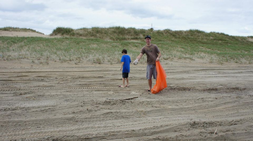 Two people on a sandy beach with sand dunes in the background.