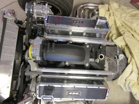 Close-up of a polished 496 engine with a supercharger and chrome valve covers.