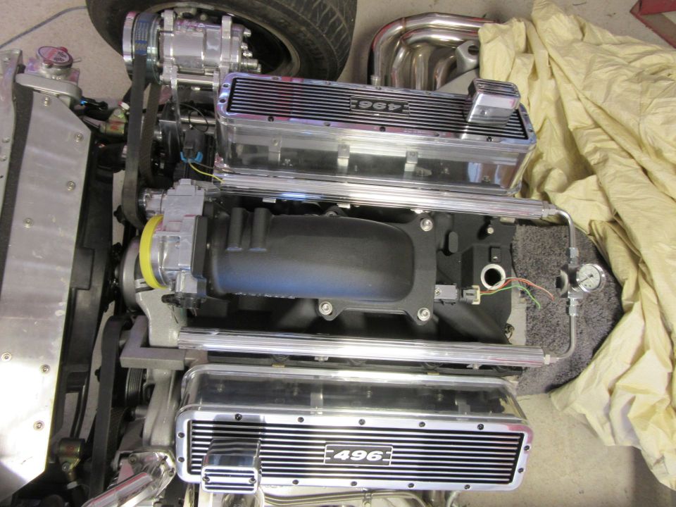 Close-up of a polished 496 engine with a supercharger and chrome valve covers.