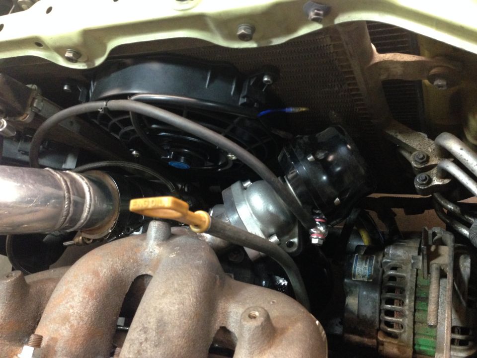 Engine bay with radiator fan, exhaust manifold, and wastegate.