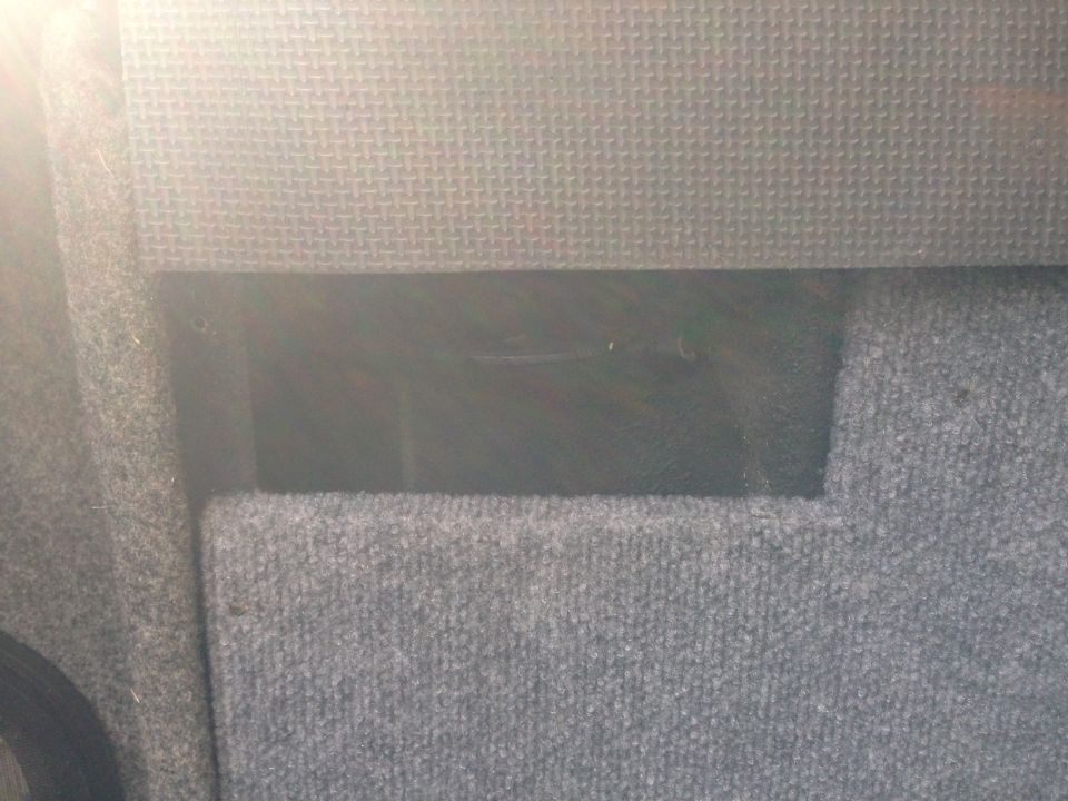 Gray carpeted interior of a vehicle with a dark opening.