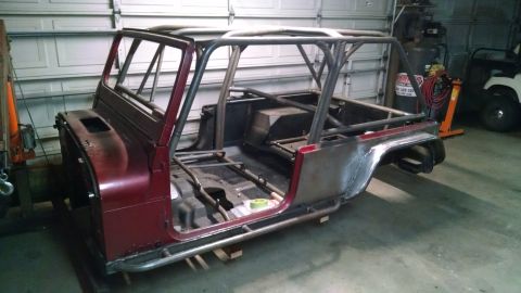 1985 Jeep CJ7 - A custom-built Jeep CJ7 tub with a roll cage is shown in a garage setting. The vehicle is partially disassembled, with exposed metal and a…