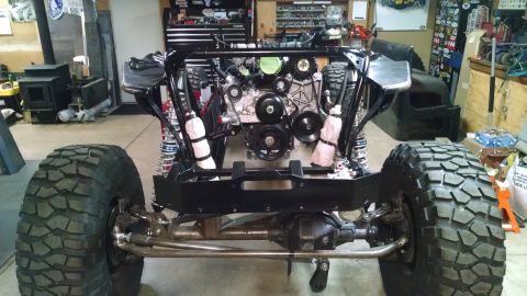 1985 Jeep CJ7 - A custom off-road vehicle build is shown in a garage setting, featuring a large engine, suspension components, and oversized tires. The veh…