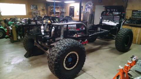 1985 Jeep CJ7 - A custom-built off-road vehicle frame with large tires is shown in a workshop setting. The vehicle appears to be a project in progress, wit…