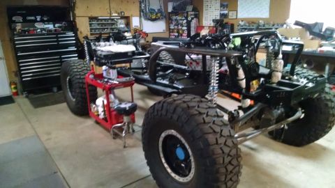 1985 Jeep CJ7 - A custom-built off-road vehicle chassis with large tires is parked in a garage next to a black toolbox. The vehicle appears to be under con…